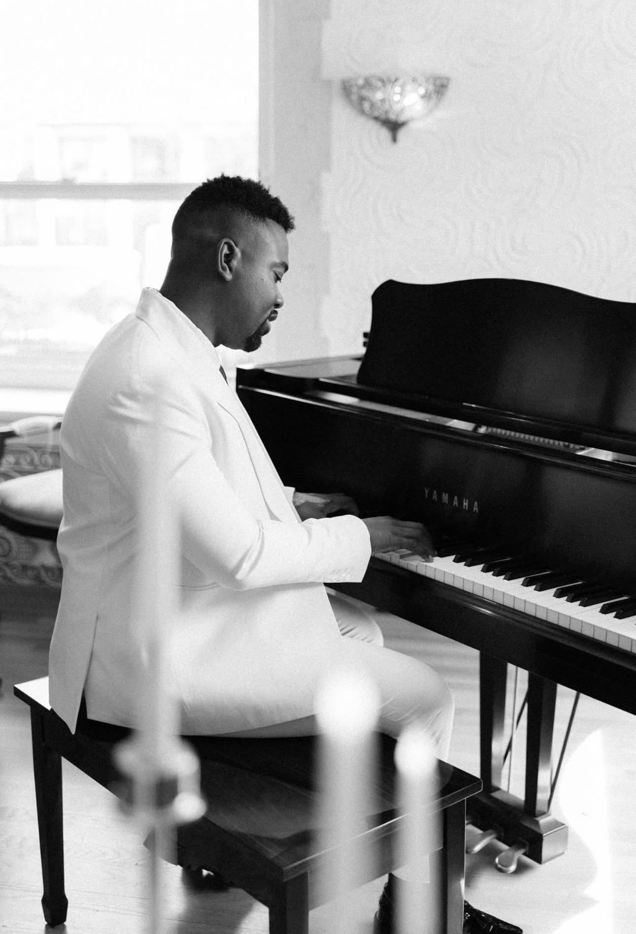 Dr. Lucas designer Jeff Magloire at the piano in a white tailored suit